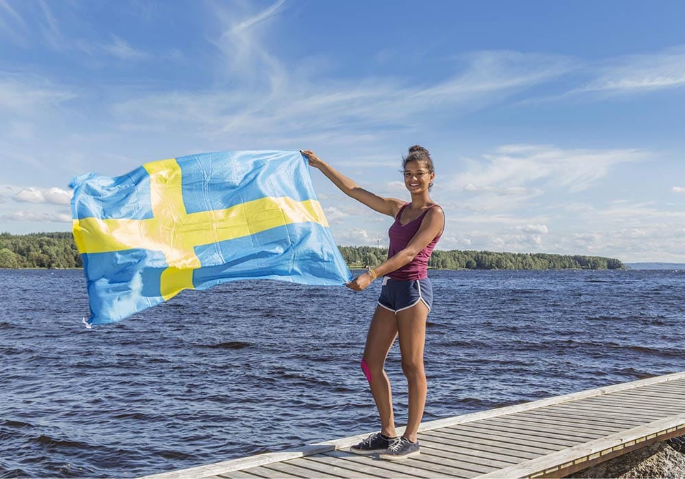 Mädchen mit Schwedenflagge am See Die schwedische Seenlandschaft ist einzigartig.